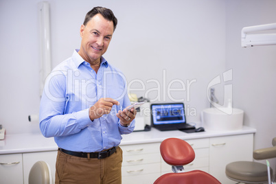 Portrait of smiling dentist using mobile phone