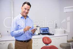 Portrait of smiling dentist using mobile phone
