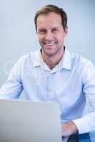 Portrait of smiling dentist working on laptop