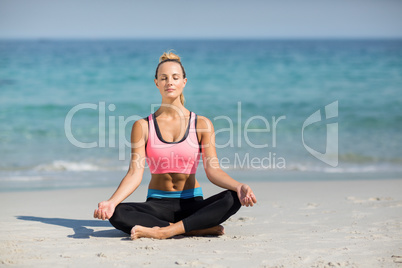 Woman meditating in lotus position at beach