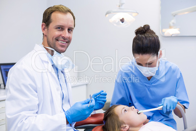 Dentist examining a young patient with tools