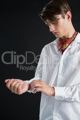 Androgynous man buttoning his shirt sleeve