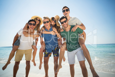 Men piggybacking friends at beach