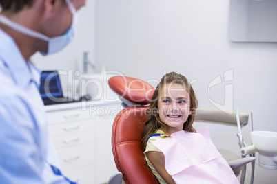 Smiling dentist talking to young patient