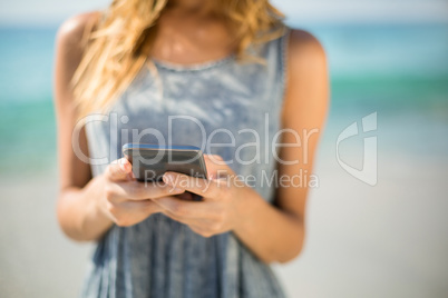 Midsection of woman using mobile phone at beach