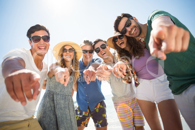 Friends pointing while standing against sky