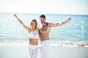 Couple standing with arms outstretched on shore at beach