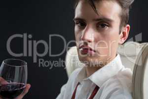 Androgynous man holding wine glass against black background