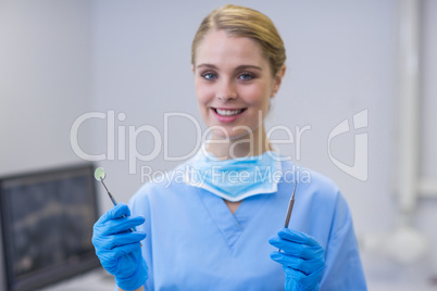 Portrait of happy female nurse holding dental tools