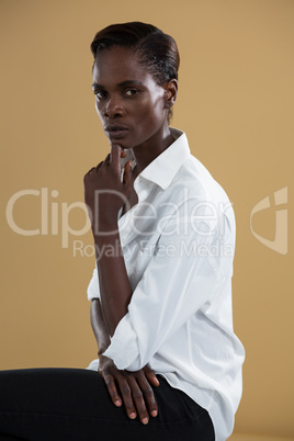 Androgynous man in white shirt posing against beige background