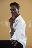 Androgynous man in white shirt posing against beige background