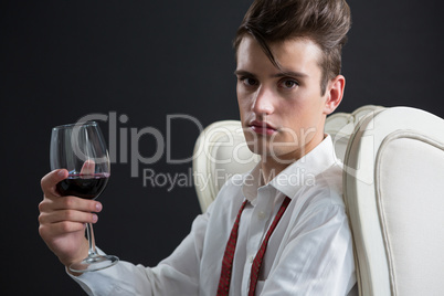 Androgynous man holding wine glass against black background