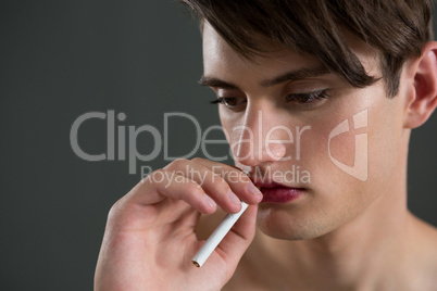 Androgynous man posing with cigarette in his mouth