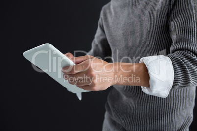 Androgynous man using digital tablet against black background