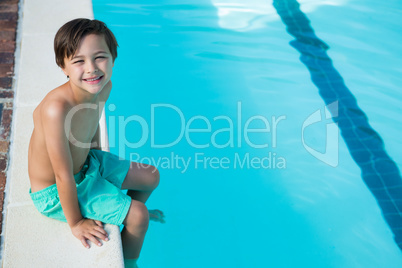 Smiling boy sitting at poolside