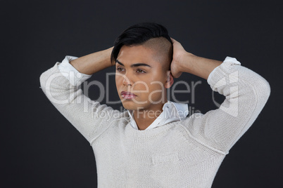Transgender woman with arms raised over black background