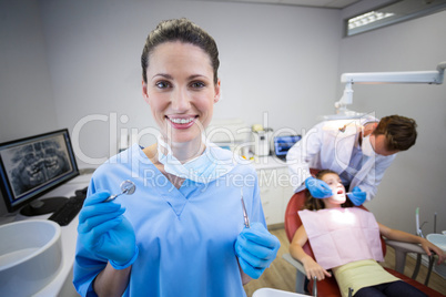 Portrait of nurse holding dental tool in clinic
