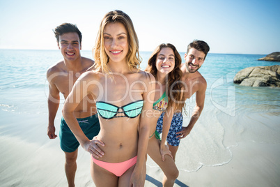 Happy friends standing on shore at beach