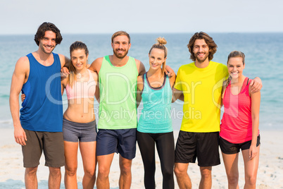 Happy friends standing with arm around at beach