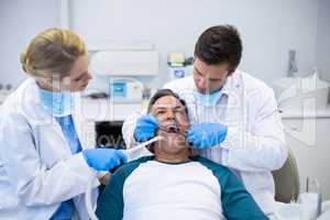 Dentists examining a male patient with tools