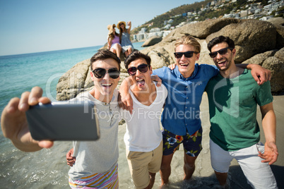 Male friends taking selfie at beach