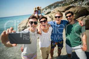 Male friends taking selfie at beach
