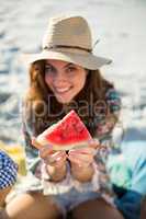 Happy woman showing watermelon at beach