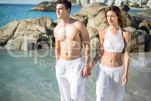 Couple holding hands while walking on shore