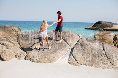 Couple holding hands while standing on rock at beach