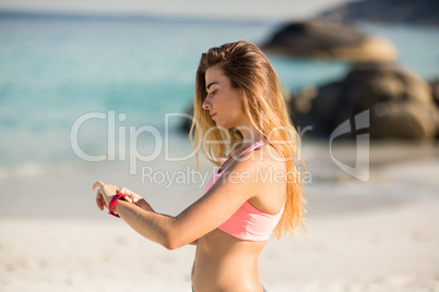 Woman looking at wristwatch while standing on shore