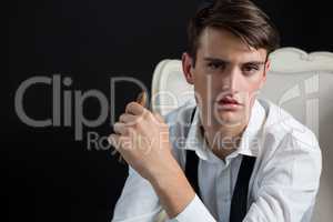 Androgynous man sitting on chair with cigar