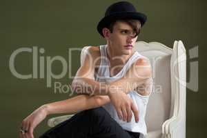 Androgynous man in hat sitting on chair