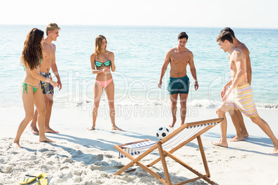 Friends playing soccer on shore at beach