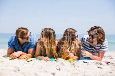 Happy friends lying on sand at beach