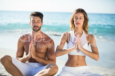 Couple meditating while sitting on shore