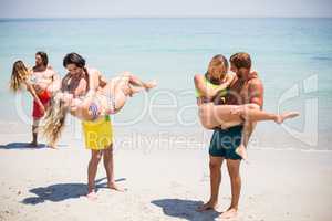 Men lifting women while standing at beach
