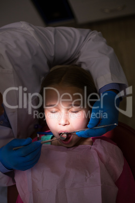 Dentist examining a young patient with tools