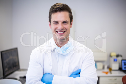 Portrait of happy dentist standing with arms crossed