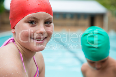 Smiling girl with swim cap near poolside