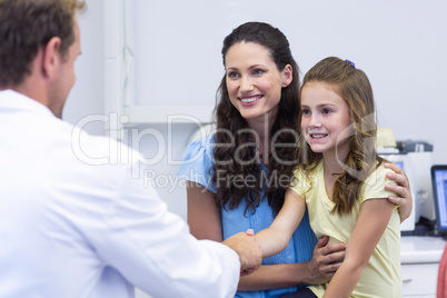 Dentist shaking hand with daughter after dental examination