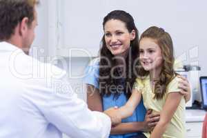 Dentist shaking hand with daughter after dental examination