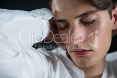 Androgynous man posing in open buttondown shirt with eyes closed