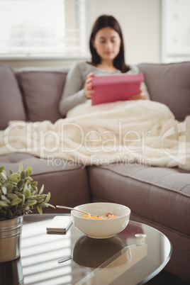 Close up breakfast on table while woman sitting on sofa