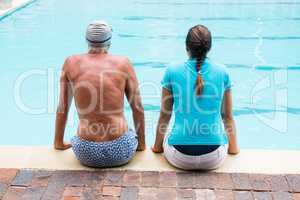 Female coach and senior man sitting at poolside