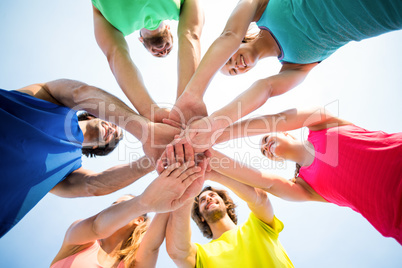 Friends standing with stacked hands against sky