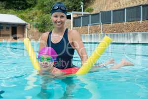Female instructor training young girl in pool
