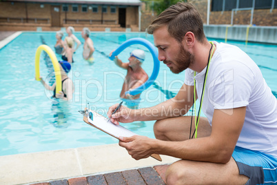 Swim coach writing on clipboard