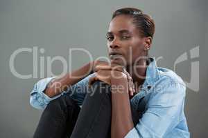 Androgynous man in denim shirt posing against grey background