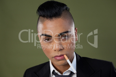 Transgender woman with cigarette in mouth over green background