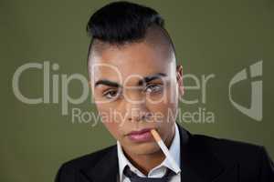 Transgender woman with cigarette in mouth over green background